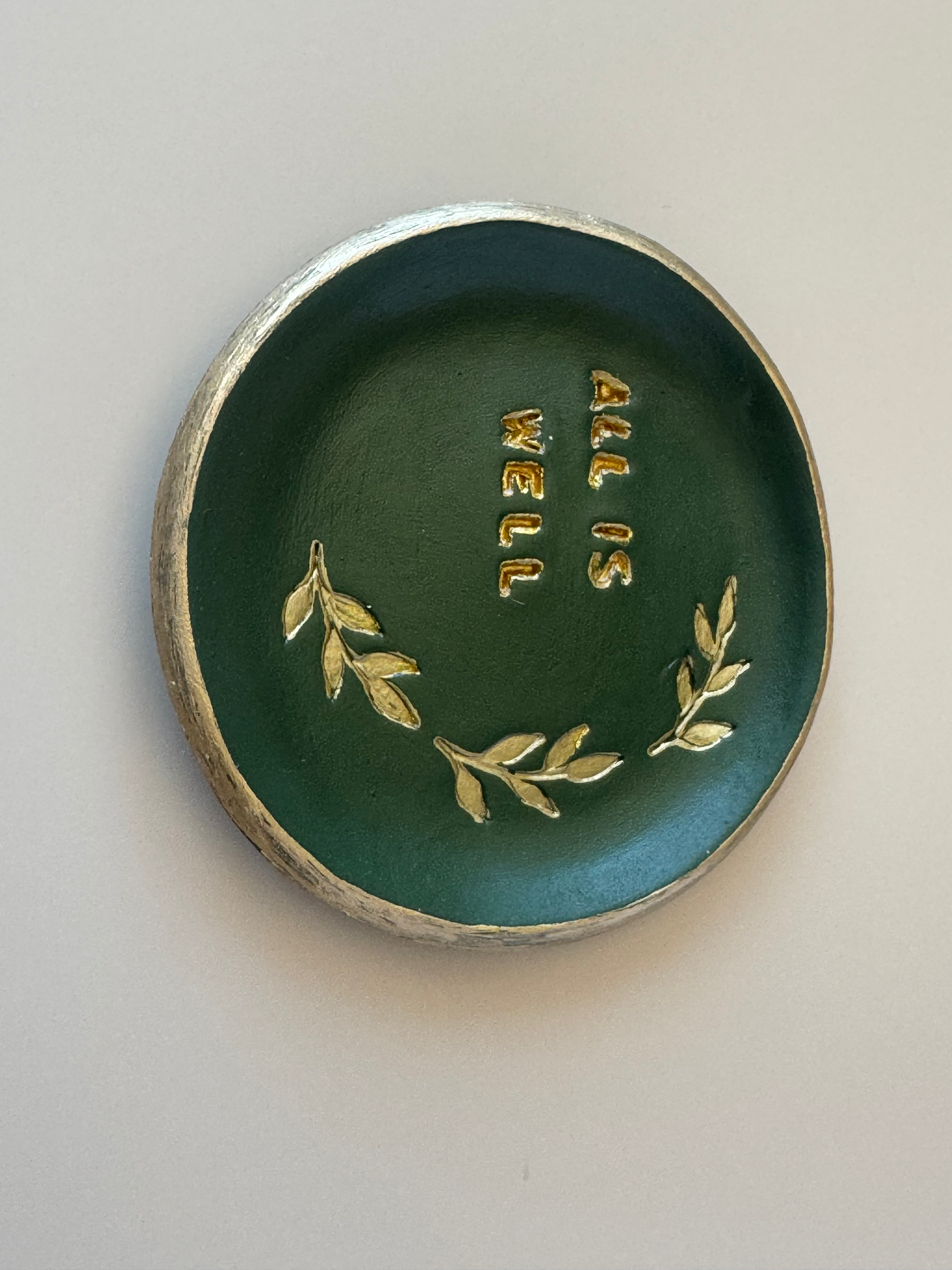 Handmade clay All Is Well — Clay Bowl in deep forest green with gold All Is Well inscription and botanical leaf motif