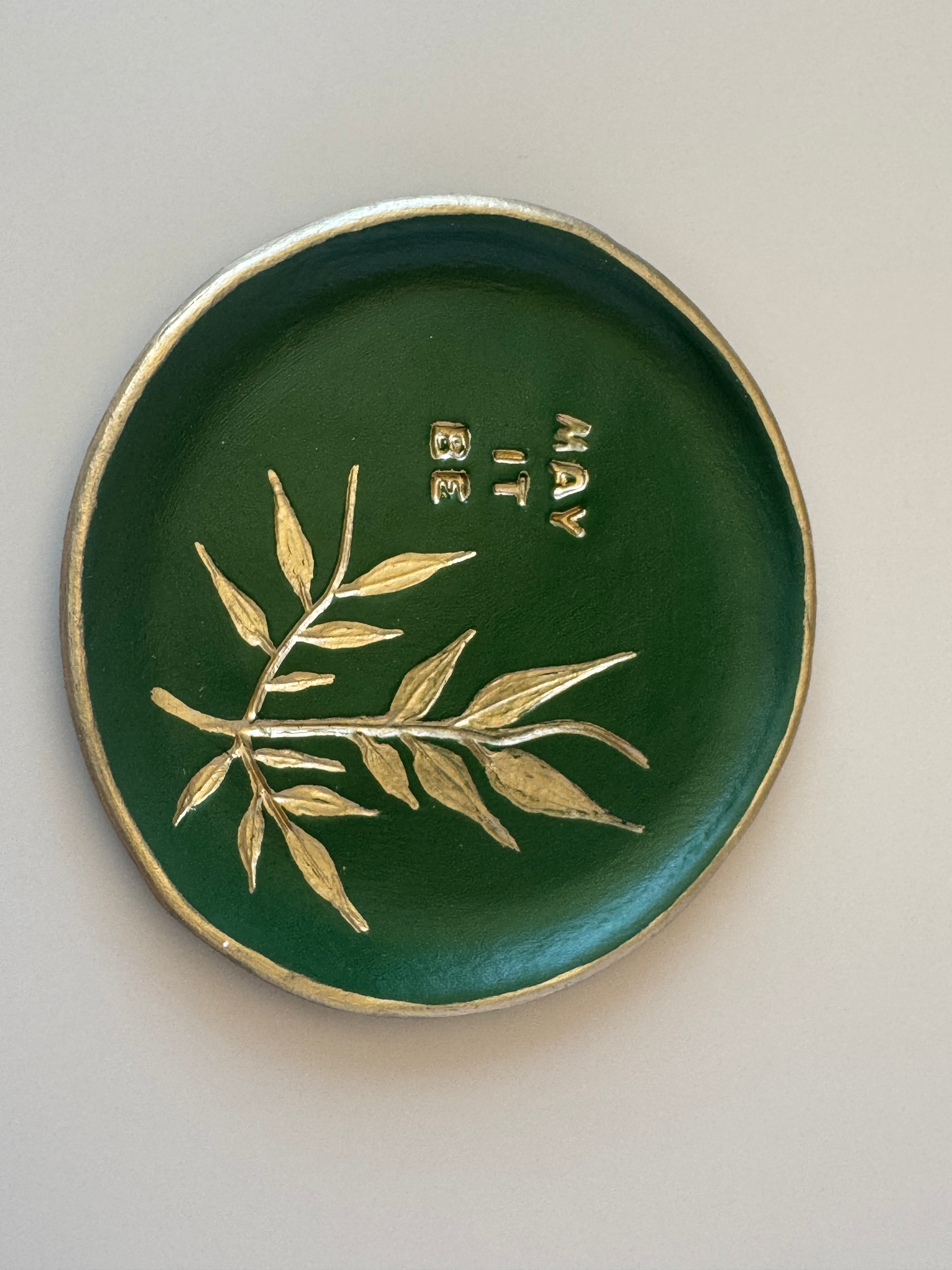 Handmade clay May It Be — Clay Plate in deep forest green with gold May It Be inscription and botanical leaf motif
